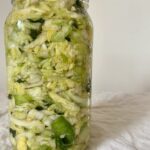 Canning jar filled with a mix of cabbage, leeks, stinging nettle, lemon, and garlic.